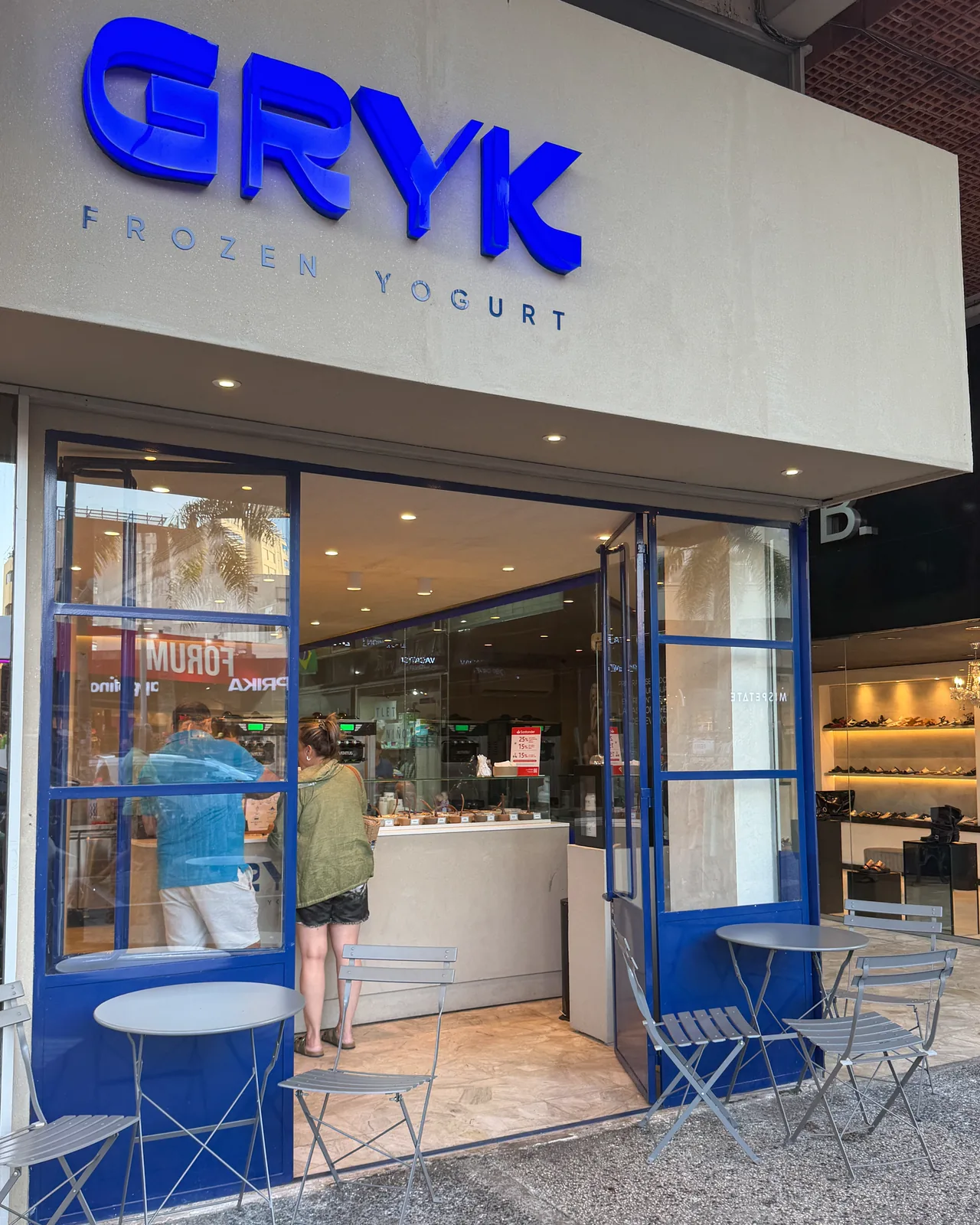 Local de GRYK en Gorlero, Punta del Este: cartel azul, vidriera con marcos azules y mesas en la vereda