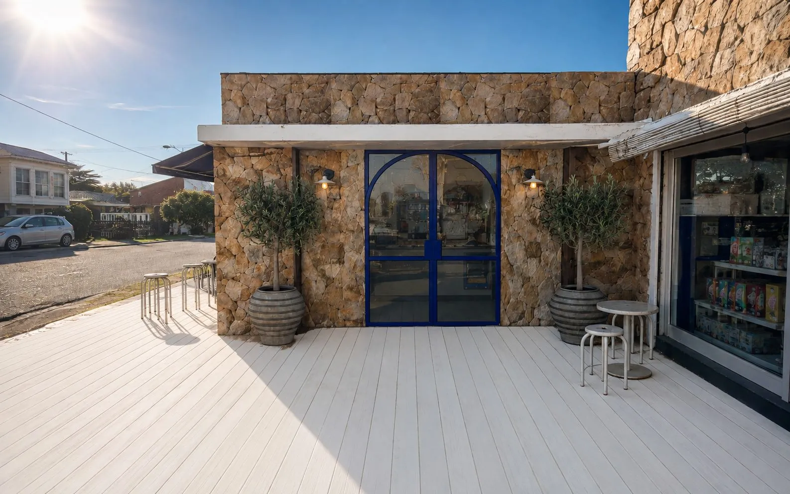 Render del local de La Barra: fachada de piedra, puerta en arco azul y deck